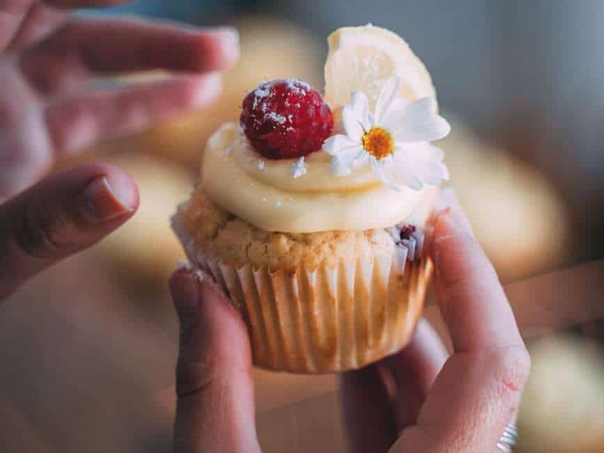 person holding cupcake with white icing